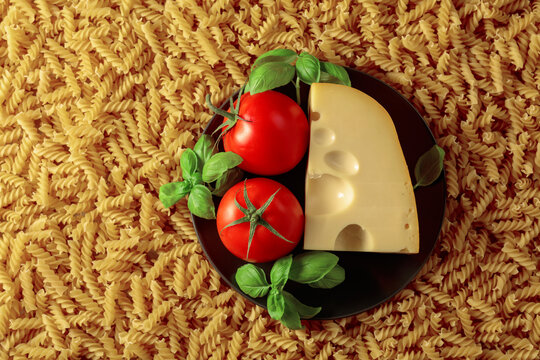 Uncooked pasta with tomatoes, basil and cheese.