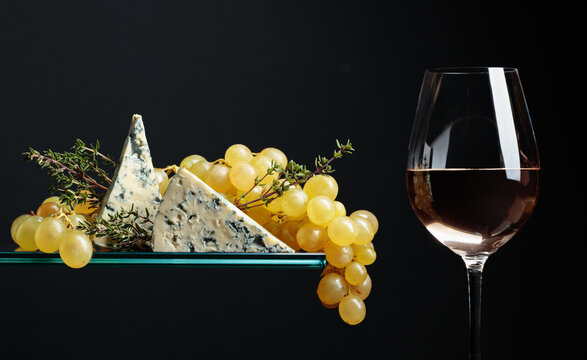 Glass of white wine with grapes, blue cheese and thyme.