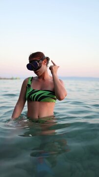 Vertical screen female diver demonstrates scuba hand signals for a problem then points to her ears to show strong pressures and explains how to equalize safely underwater