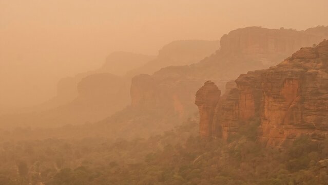 Hazy Red Sandstone Escarpment and Valleys During a Dust Storm