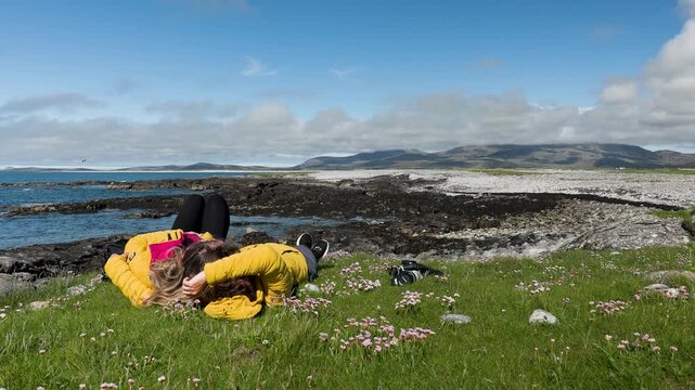 A couple lying in the grass above pristine coastal scenery on South Uist in the Outer Hebrides, Scotland