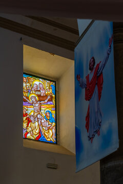 Crucifixion window beside hanging Jesus banner