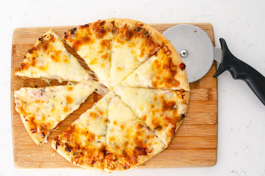 Sliced cheese pizza with pizza cutter