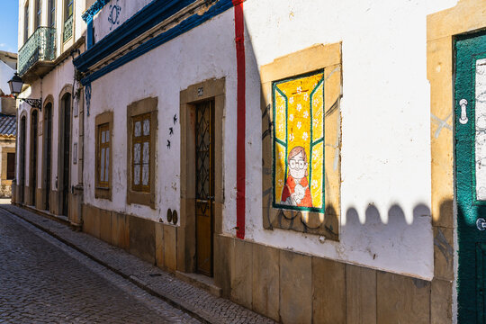 Colorful mural on whitewashed cobblestone street facade