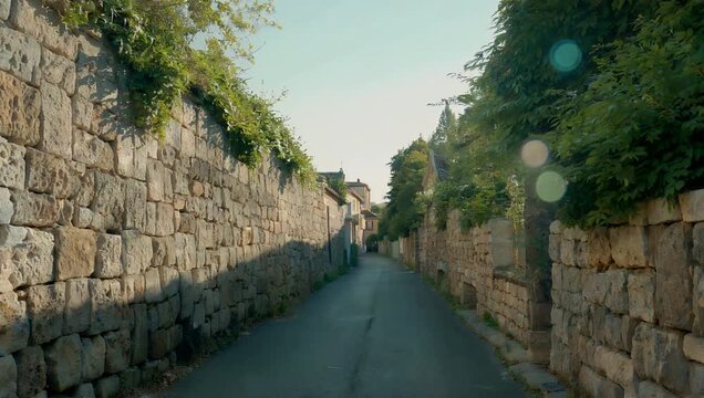 Softly blurred 4K outdoor travel b-roll displaying an empty historic European-style alleyway enclosed by ancient stone walls warmed by natural afternoon sunlight creating a soft dreamlike