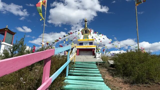 Russia - August 12, 2025: Tibetan stupa with colorful prayer flags fluttering in the wind under a clear blue sky, highlighting intricate architectural details