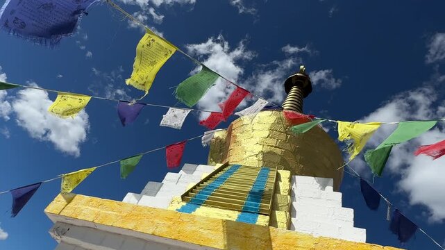 Russia - August 12, 2025: Tibetan stupa with colorful prayer flags fluttering in the wind under a clear blue sky, highlighting intricate architectural details