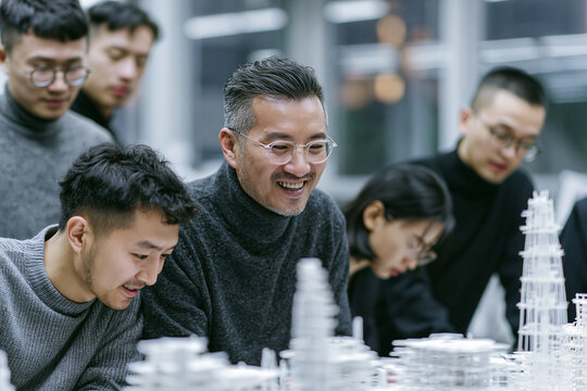 Asian Architects Team Collaborating Over Building Model in Studio