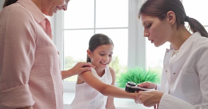 Dermatologist examines child skin with dermatoscope. Mother supports the patient during examination and mole check in a bright healthcare clinic. Pediatric preventive care and early diagnosis.