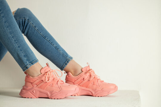 detail of sitting woman wearing pink trainers and jeans