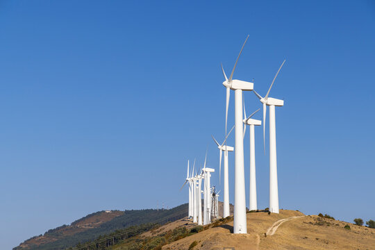 Wind turbines generating clean energy on a hilltop under a clear blue sky