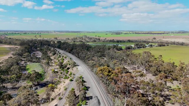 An aerial view of the Serviceton railway corridor passing through open farmland and native bushland in Rowsley, Victoria Australia. Single-track rail line, rural land near Bacchus Marsh.