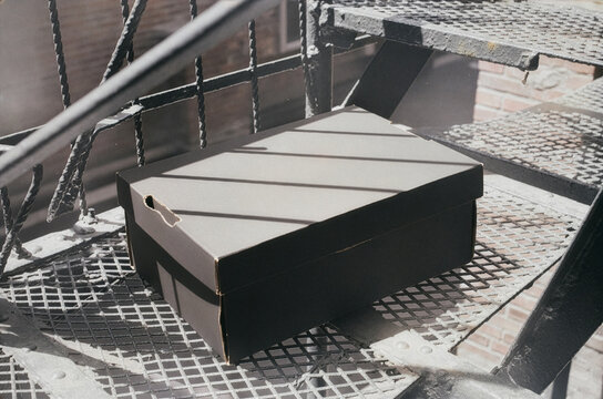 Blank black product box packaging mockup template on outdoor metal surface