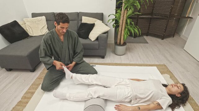 Shiatsu therapist mobilizing female clients foot during treatment