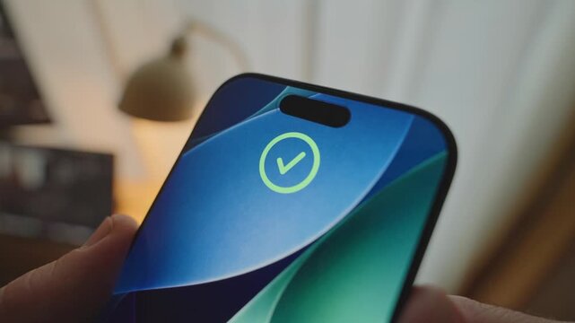 Hand holding up phone to unlock device using facial recognition technology. Close up on person's hands lifting mobile to access system with biometrics of facial features showing animation on screen