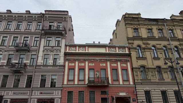 Street view of a row of historical European buildings including an old red mansion with classical sculptures on the facade.