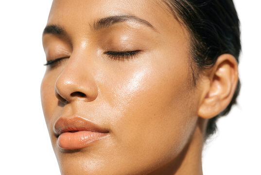 Primer plano de una mujer joven con piel radiante y natural, ojos cerrados y expresi&oacute;n serena, destacando la belleza saludable, el cuidado facial y la luminosidad cut&aacute;nea sobre fondo blanco
