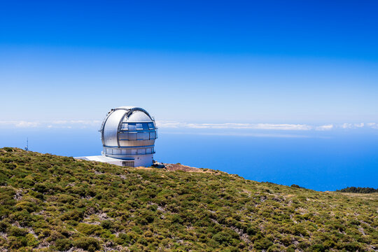Gran Telescopio Canarias observatory dome above mountain vegetation and sea, La Palma.