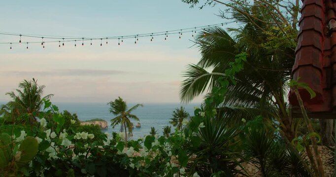 String lights hang above ocean view with palm trees in Nusa Penida Bali Island