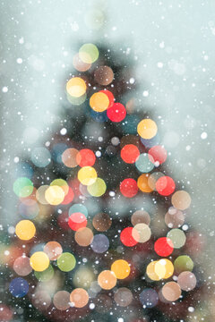 Christmas Tree Silhouette with Warm and Cool Bokeh Lights on Blue Background with Copy Space. Snowflakes are falling