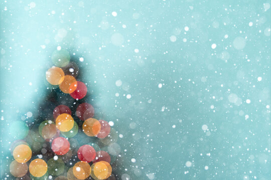 Close Up Christmas Tree Silhouette with Glowing Bokeh Lights and Copy Space. Snowflakes are falling