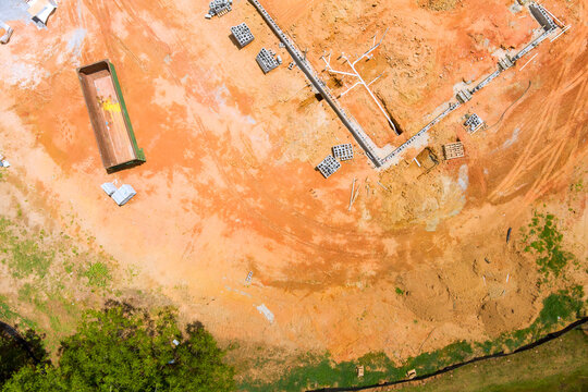 Workers are preparing ground for new building foundation at construction site, materials are placed around area.