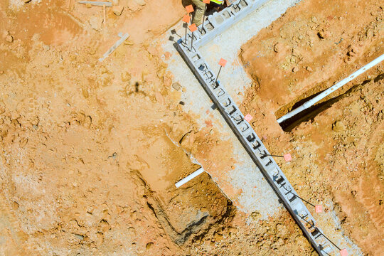 Workers are at construction site they are digging laying concrete by foundation trench in ground.