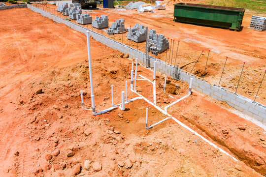Workers are laying out pipes blocks for building foundation in construction area