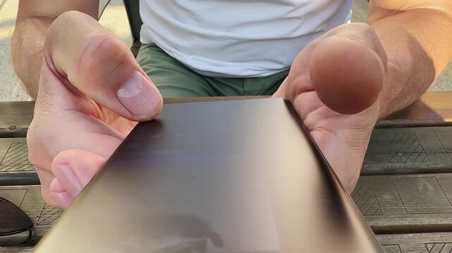 User thumb tapping dark smartphone touchscreen to send text message. Male hand holding mobile phone device typing response in chat application. Close view of thumb operation on black