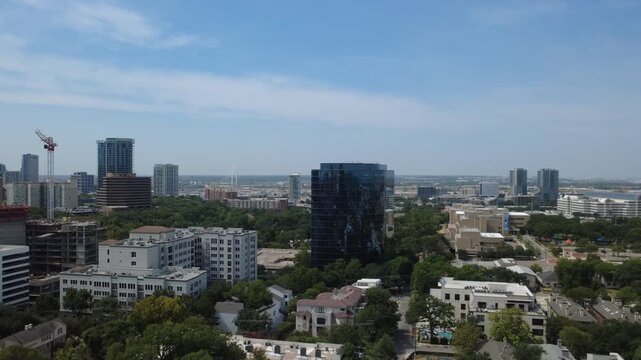 Reflective curved office tower anchors sprawling metropolitan districts near Turtle Creek, Dallas. Active building cranes signal ongoing urban infill progress, DFW Metropolitan Area, Texas