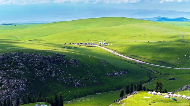 Aerial view of rolling green hills and winding road in Kalajun Grassland, Ili, Xinjiang, China
