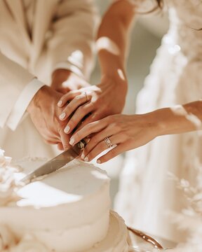 Closeup of couple hands cutting white wedding cake together with visible wedding rings and knife, with wedding, cake, hand, couple detail, showing bride, groom, ring, cutting context