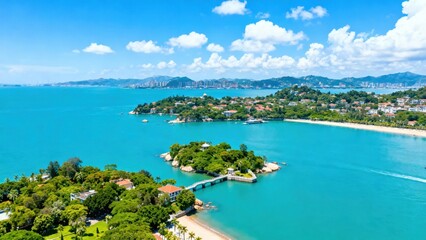 Fototapeta premium Aerial view of a tropical coastal landscape with turquoise waters, green islands, and a beachfront city under a bright blue sky