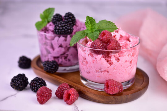 Two blackberry and raspberry sorbets with fresh berries on a light background. Close-up.
