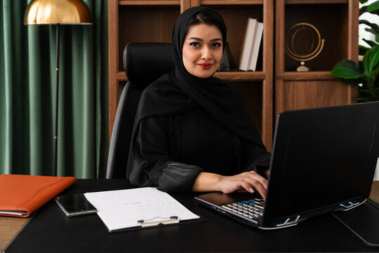 Middle-eastern female doctor or nurse wearing abaya working in the office - middle-eastern female doctor working on laptop in office
