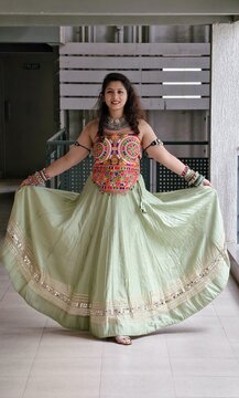 Indian woman showcasing vibrant Navratri fashion in an embroidered ethnic top and flowing mint green skirt, adorned with colorful bangles, bajubandh and oxidized jewellery in a festive Gujarati style.