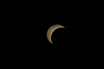 Partial solar eclipse showing a bright golden crescent in black sky © AdobeTim82