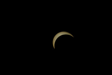 Partial solar eclipse showing a bright golden crescent in black sky © AdobeTim82