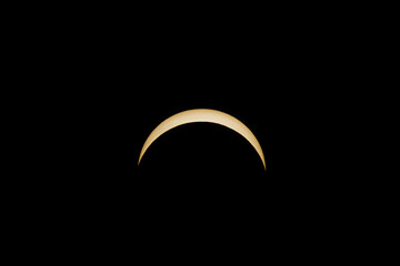 Partial solar eclipse showing a bright golden crescent in black sky © AdobeTim82