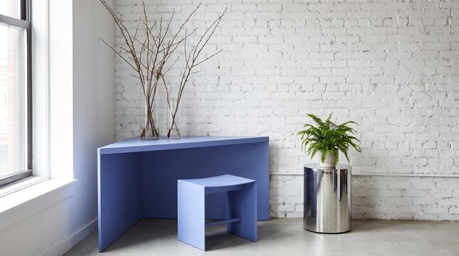 Modern periwinkle blue desk and stool in minimalist white brick interior with natural light and greenery