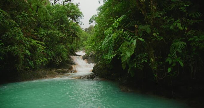 Summer travel at Costa Rica Blue Falls with turquoise river flowing through lush jungle