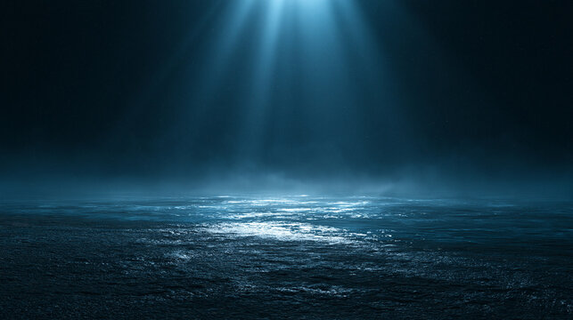 Dramatic blue spotlight shining on a dark empty stage with textured ground and atmospheric smoke. Perfect background for product display or creative conceptual compositions.
