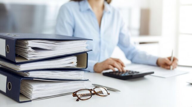 Internal audit and tax concept featuring binders with papers waiting to be processed by a bookkeeper or business woman.