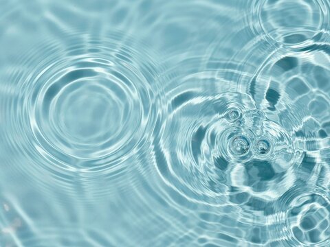 Top view of clear blue water ripples with air bubbles for spa and wellness background designs.