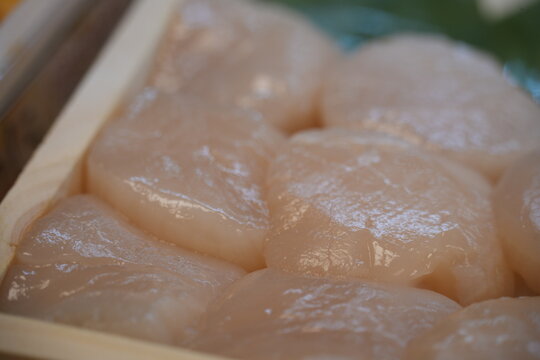 A close up view of fresh raw scallops in a wooden box.