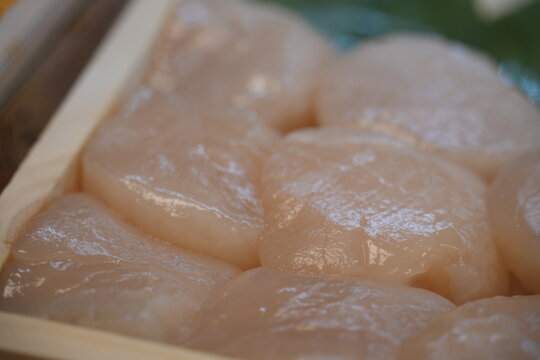 A close up view of fresh raw scallops in a wooden box.