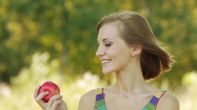 Young beautiful woman eating ripe red apple