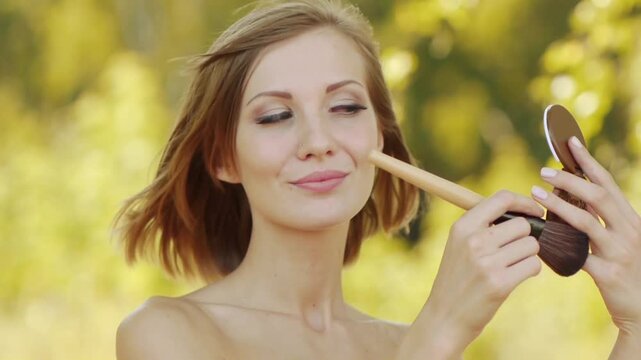 Young beautiful woman puts foundation on face