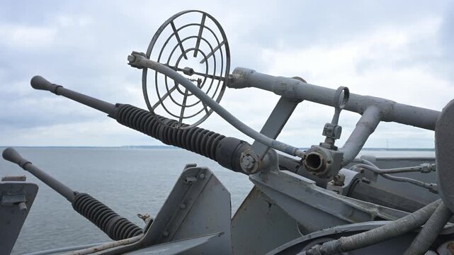 Deck-mounted vintage naval cannon with targeting sights on a military vessel, sea background.