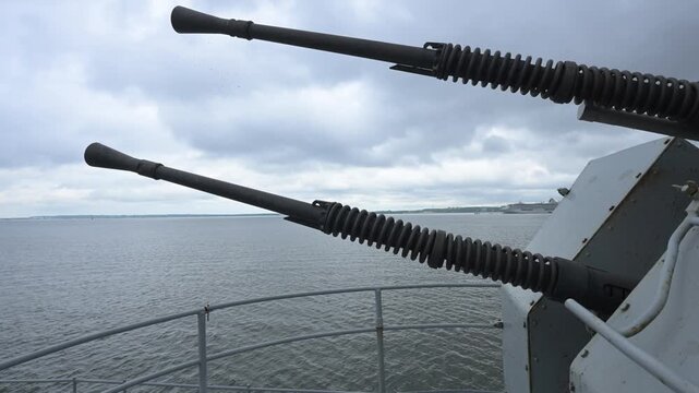 Close-up of twin 20mm Oerlikon naval anti-aircraft guns on a museum ship, sea background.